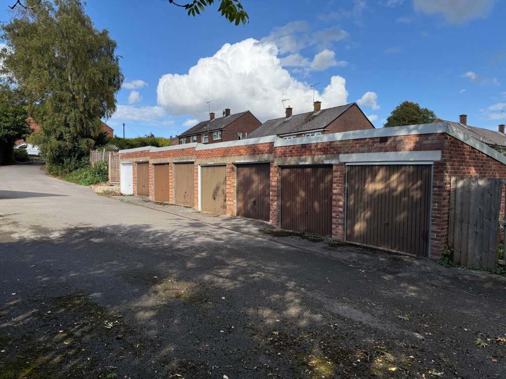 Lot: 173 - GARAGE BLOCK WITH CONSENT FOR CONSTRUCTION OF TWO HOUSES - Block of eight garages looking up the hill